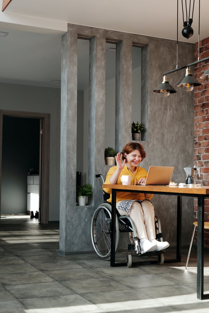 woman in wheelchair greeting someone on an online call